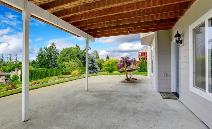 A tranquil concrete patio enveloped by lush greenery offers a serene oasis, seamlessly blending the urban with the natural in a harmonious retreat