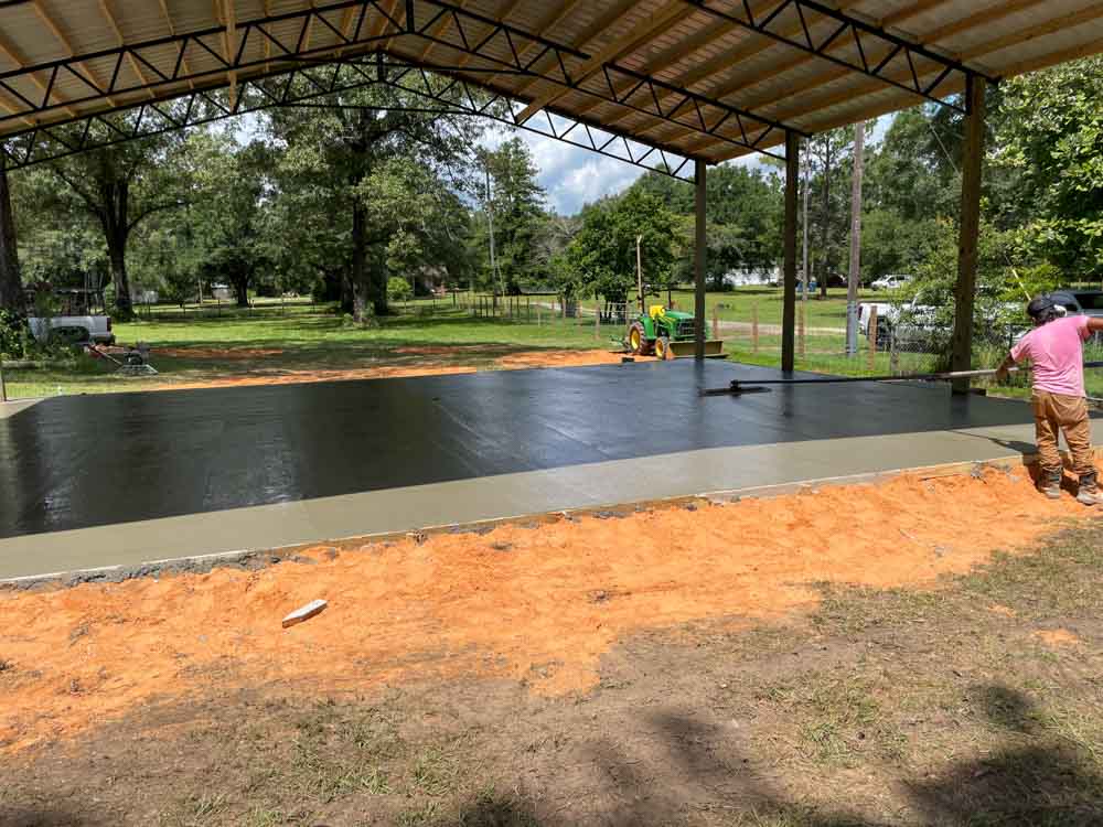 A covered concrete deck in the backyard emerges as a versatile oasis, offering both shelter and open-air freedom, where relaxation meets the embrace of nature