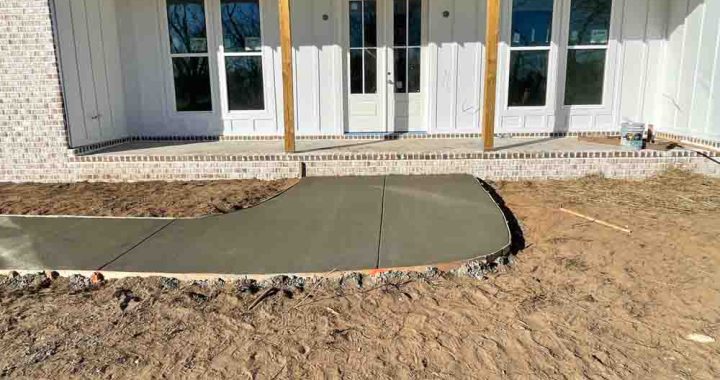 Wet concrete on a sidewalk leading to the front porch of a brick house