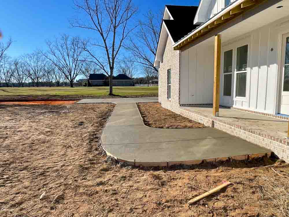 Wet concrete on a sidewalk leading to the front porch of a brick house