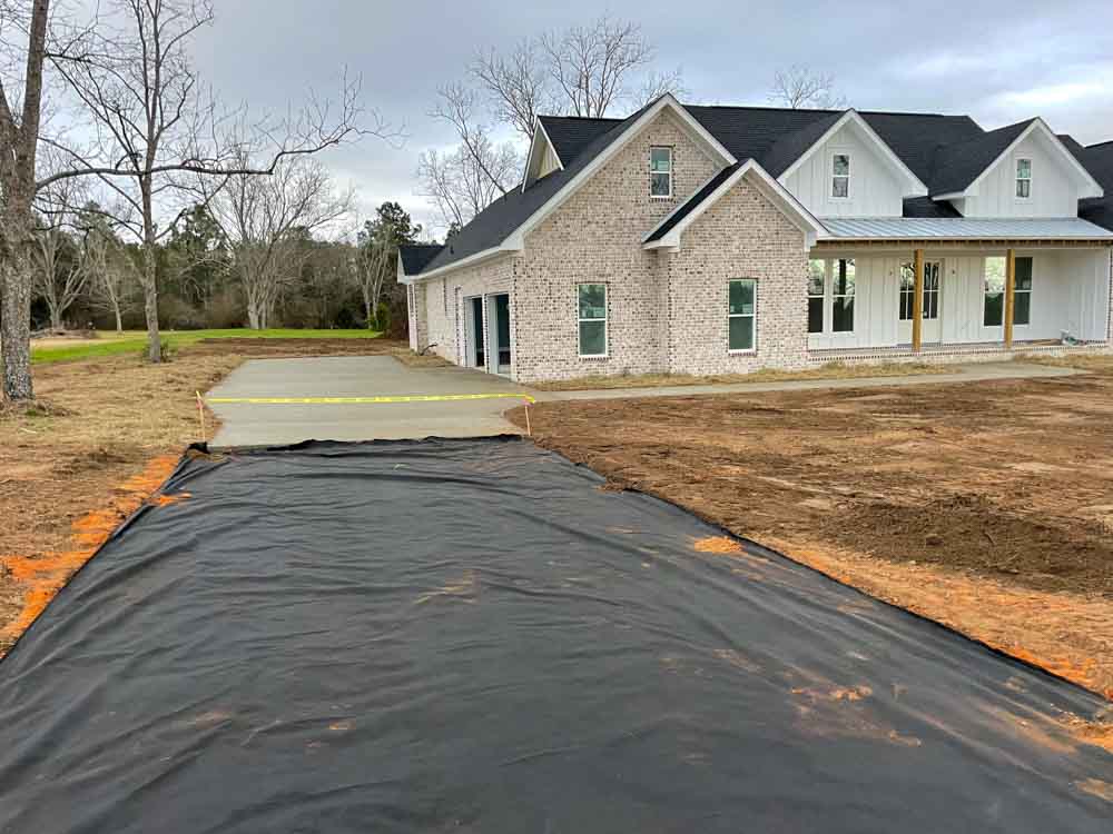 Yellow caution band marking the finished and unfinished area of an ongoing driveway concrete construction