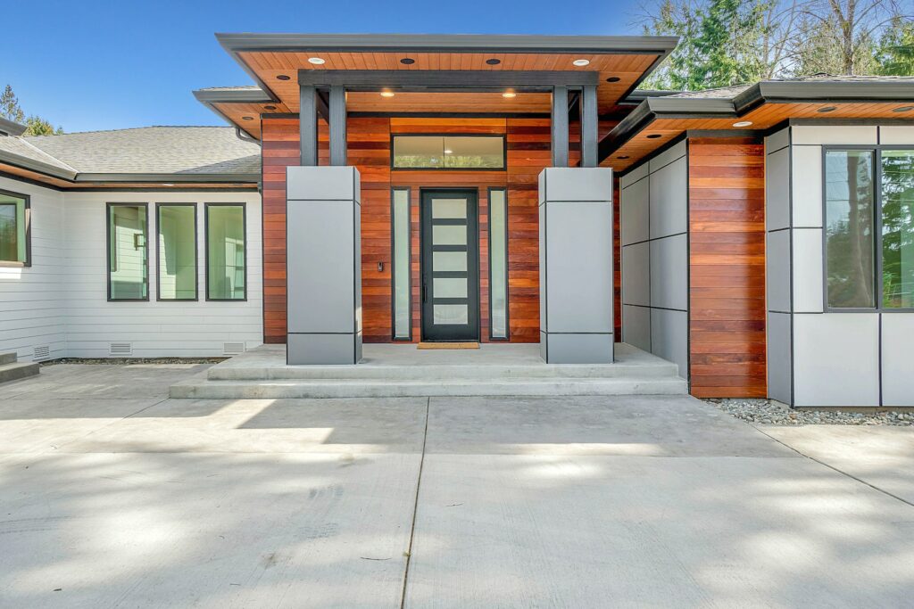 A front view of a modern and sleek house with a spacious concrete driveway
